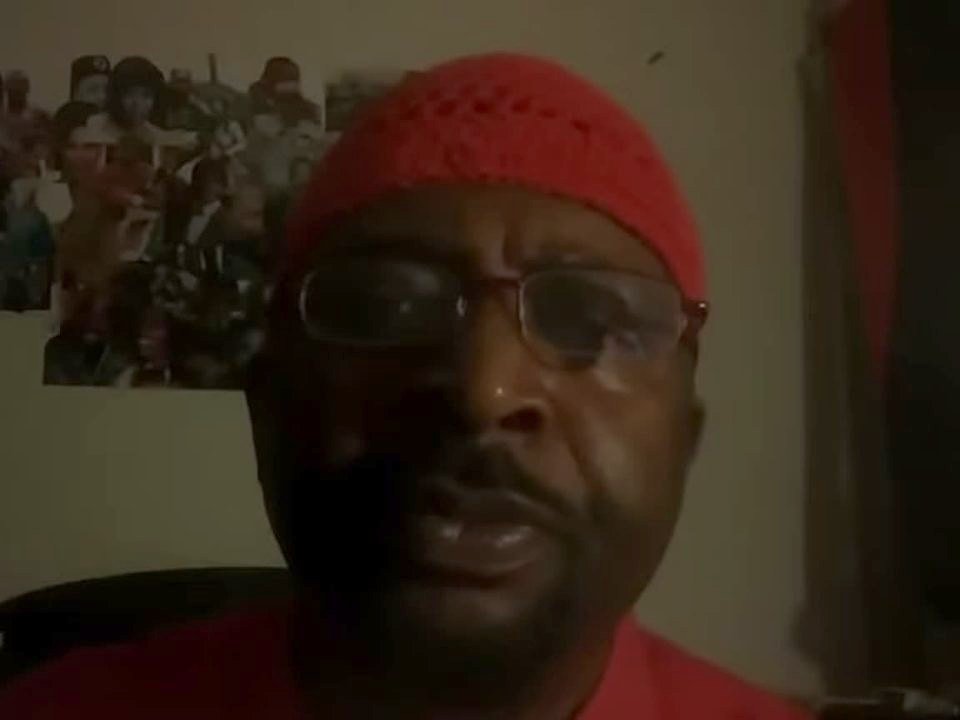 T’Shaka Sankofa speaking to camera in a red kufi
