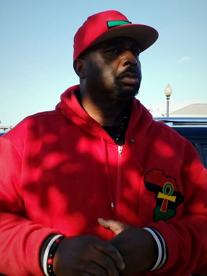 T’Shaka Sankofa in his red hoodie and cap on a Washington, DC street, a scene from the film